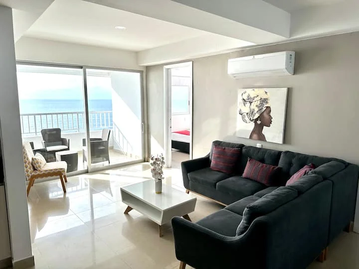 Sala con sofá oscuro y balcón frente al mar — Palmetto 1001